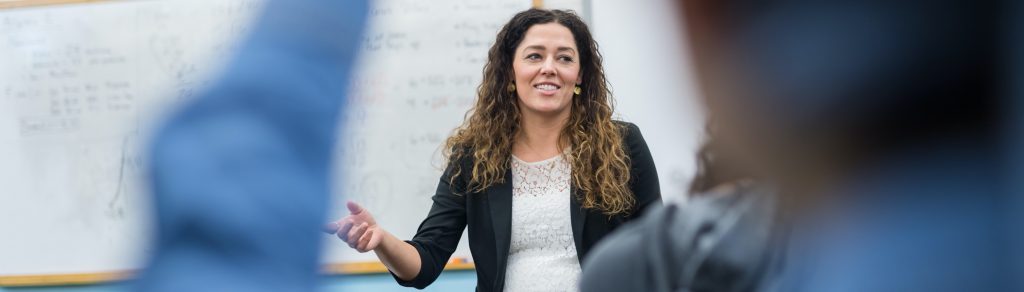 Teacher points to one of her students with a raised hand